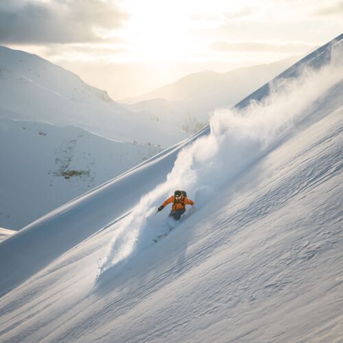 Skier in orange outfit in deep snow in the Alps