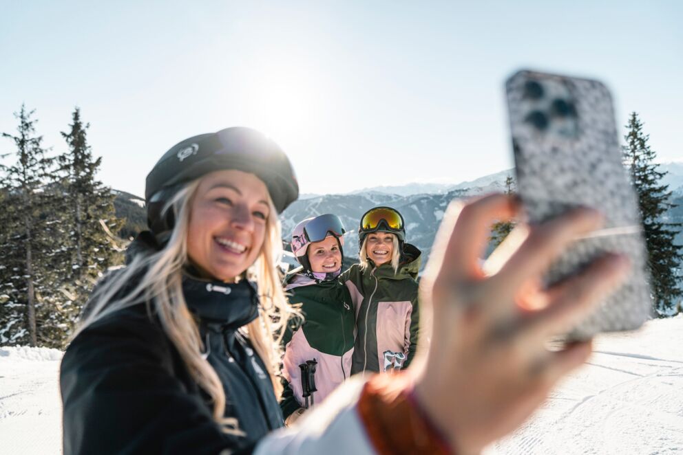 Drei Freundinnen machen ein Selfie beim Skifahren in den Bergen