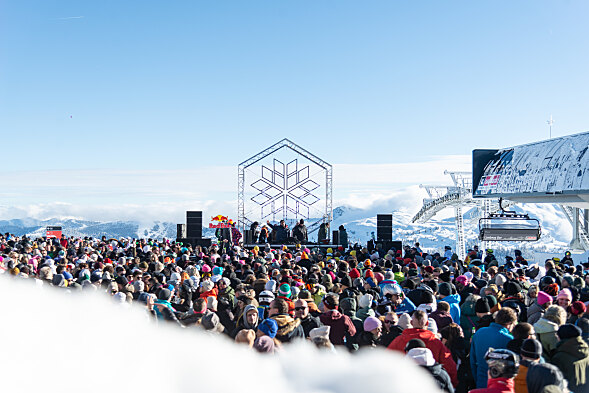 Hundere Menschen vor einem DJ Pult am Gipfel eines Berges im Winter