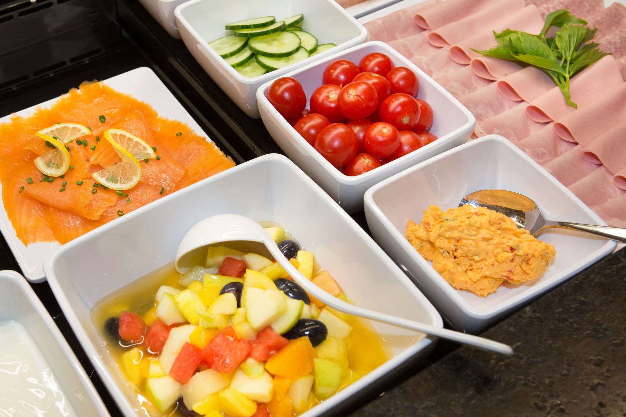Beim Frühstücksbuffet in Hinterglemm steht Wurst, Gurke, Tomaten, Lachs und ein Obstsalat zur Auswahl