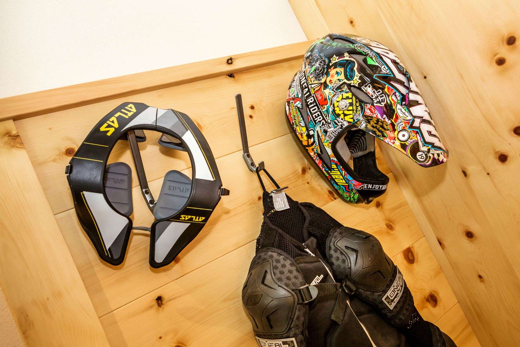 A motorbike helmet, a motorbike jacket and a motorbike protector hang on the chest of drawers