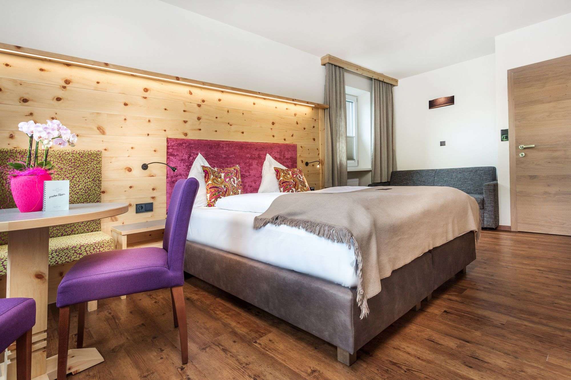Bright and modern double room with double bed, sofa and a sitting area in the Hotel Talblick in Hinterglemm.