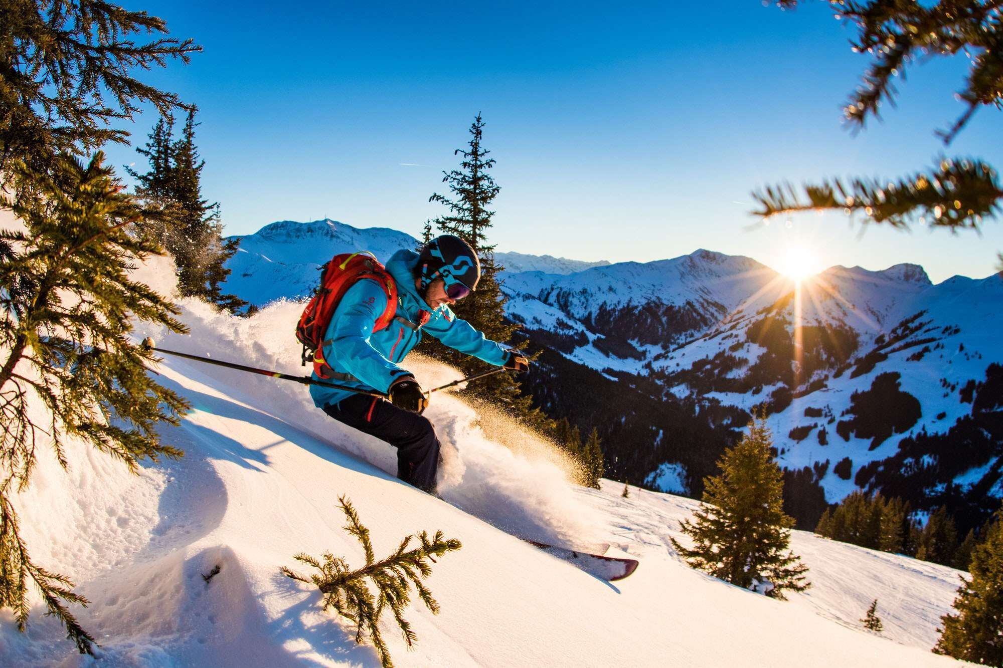Ein Freerider fahrt in der Früh zischen Bäumen den Berg in Hinterglemm hinab
