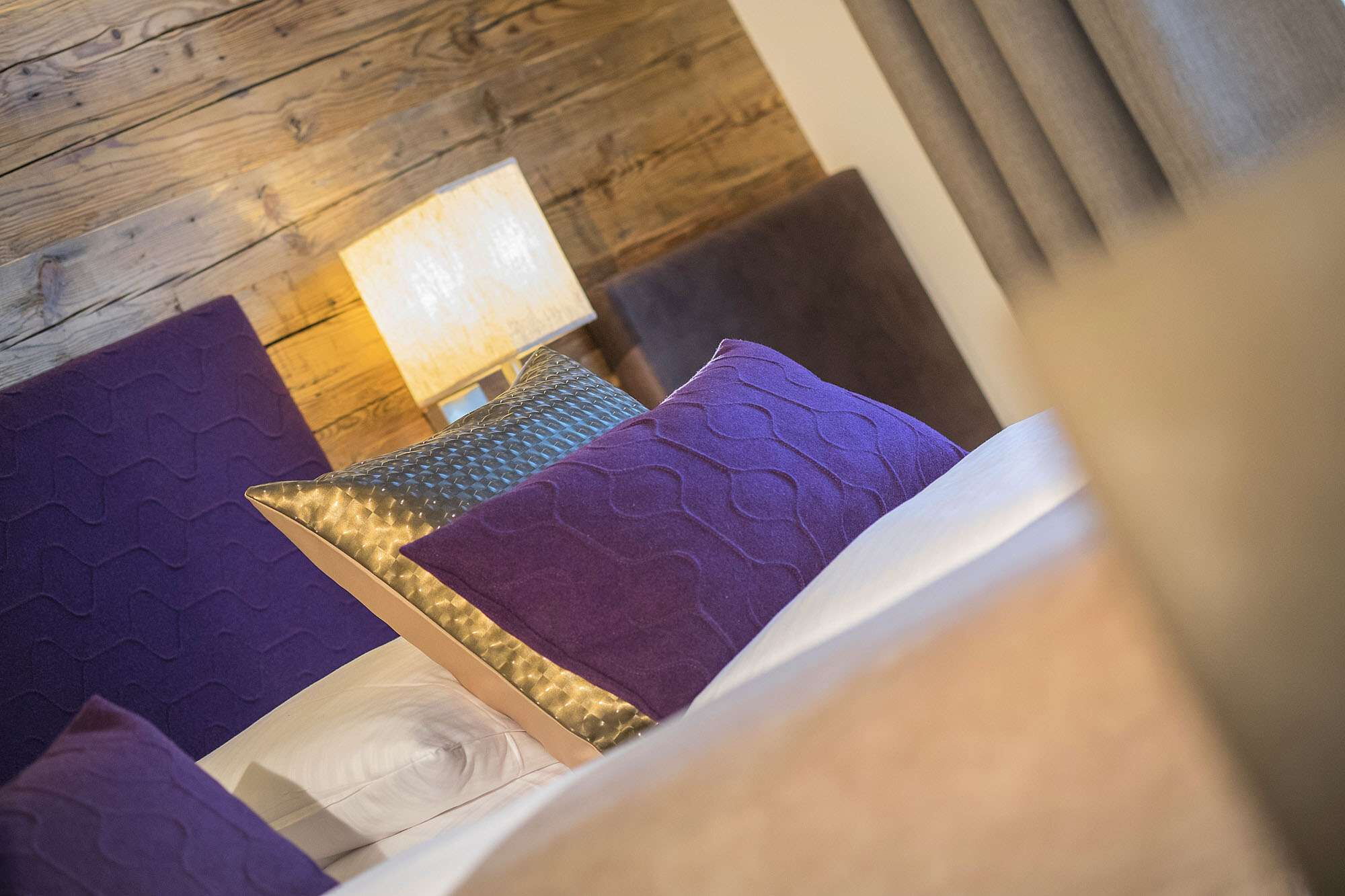 Ein violettes, ein silbernes und ein weißes Kissen liegen auf dem Bett im Hotel Talblick in Saalbach