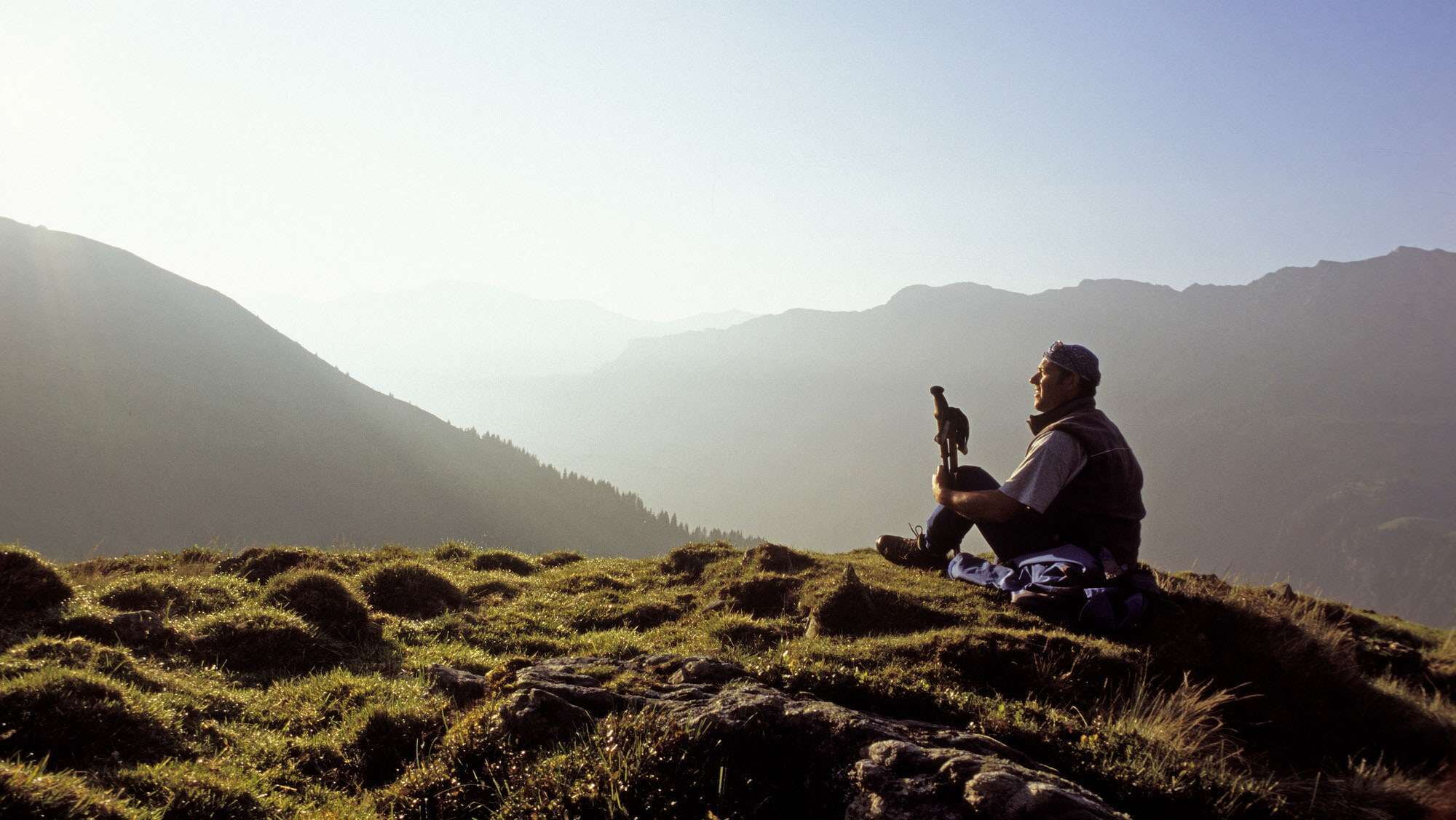 A man takes a break from hiking and looks at nature in Hinterglemm while sitting down