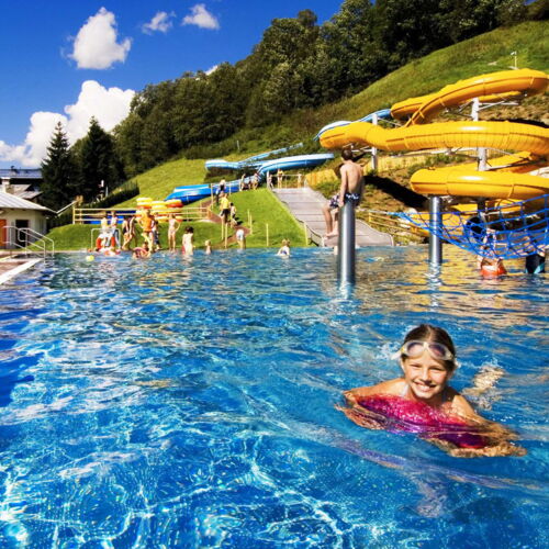 Ein Mädchen schwimmt im Erlebnisbad Käpt'n Hook in Saalbach, hinter ihr befindet sich eine Rutsche
