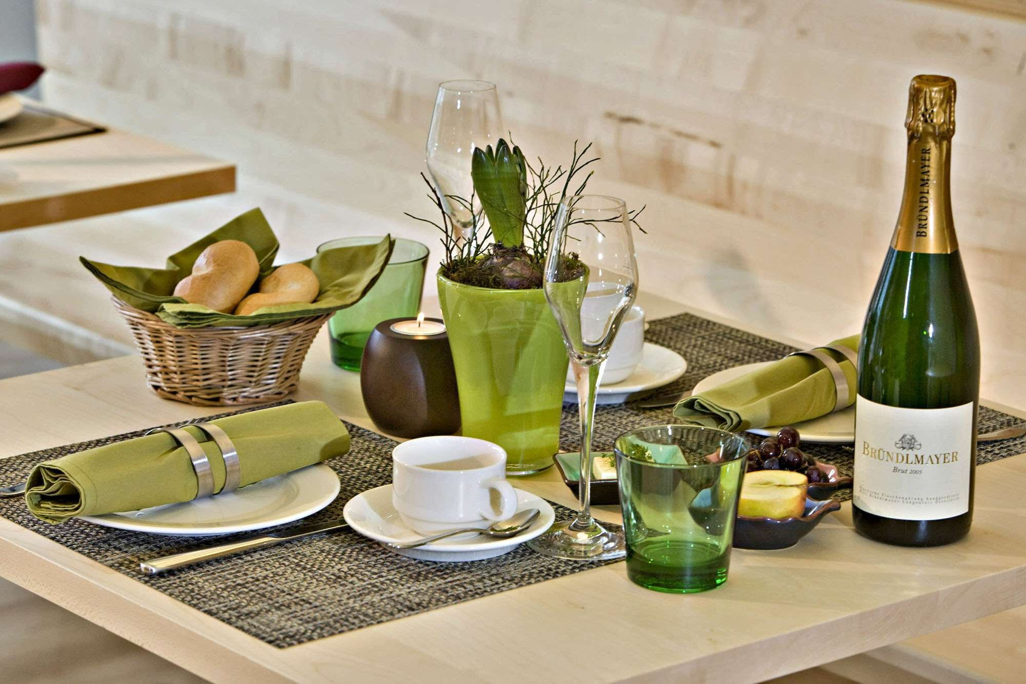 Der Frühstückstisch im Hotel Talblick in Hinterglemm, gedeckt mit Obst, Brot, Butter, Geschirr und Sekt