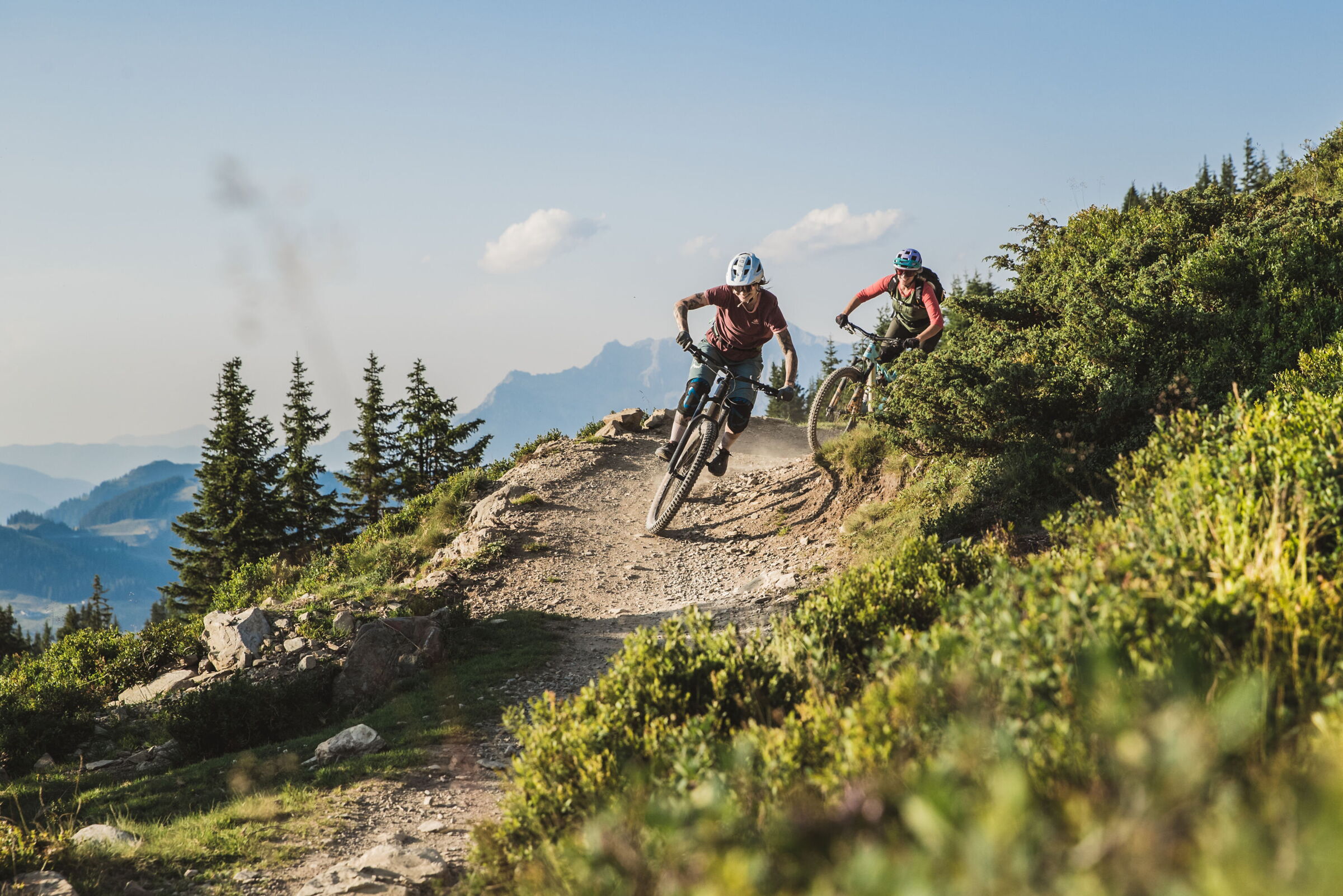 Zwei Mountainbiker auf einem Trail in alpiner Kulisse