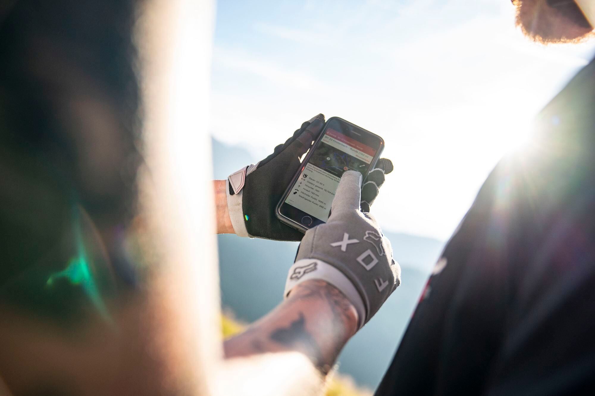 Zwei Männer sehen sich am Handy den Interaktiven Radroutenplaner an