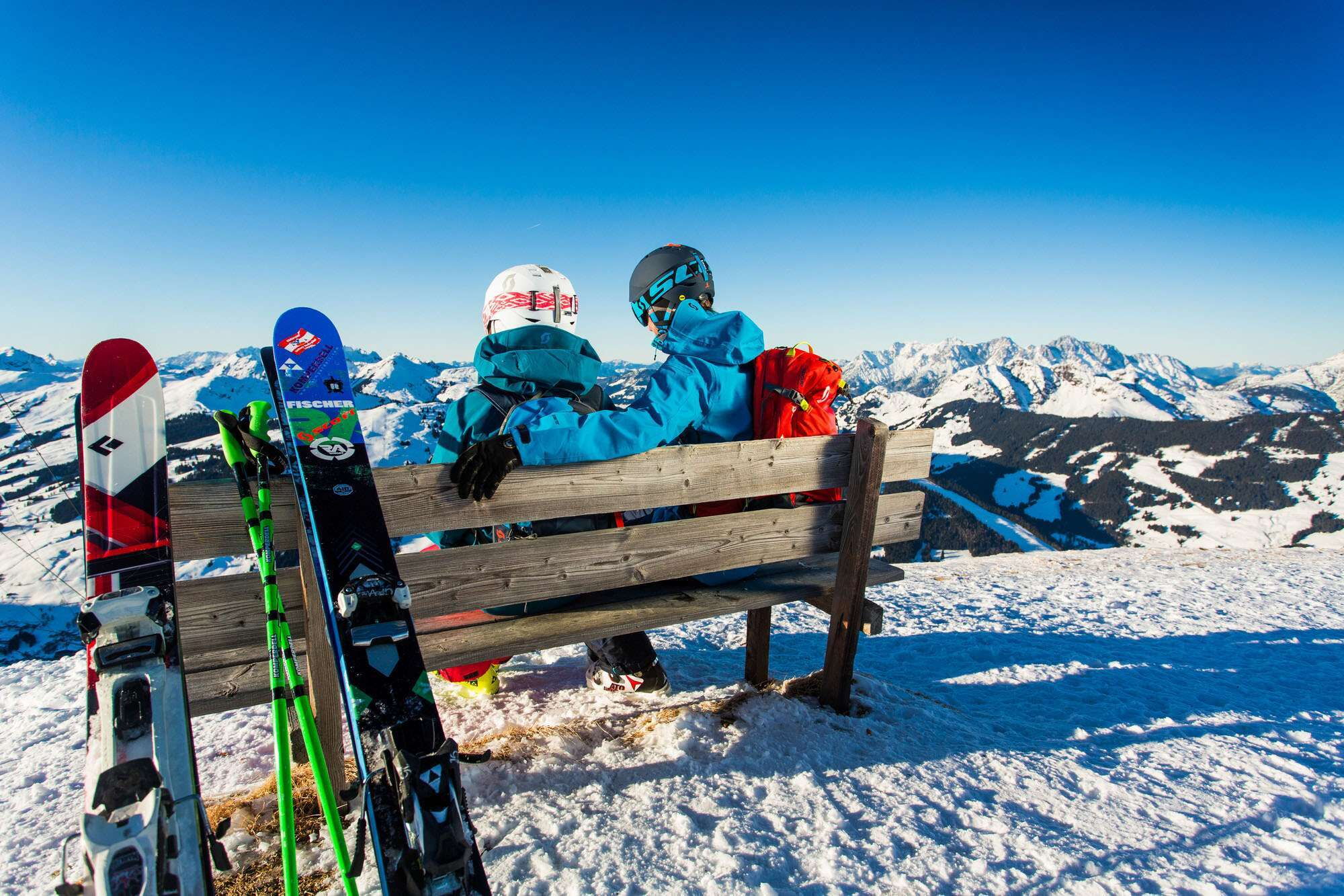 Ein Paar macht eine Ski-Pause bei einer Bank in den Bergen