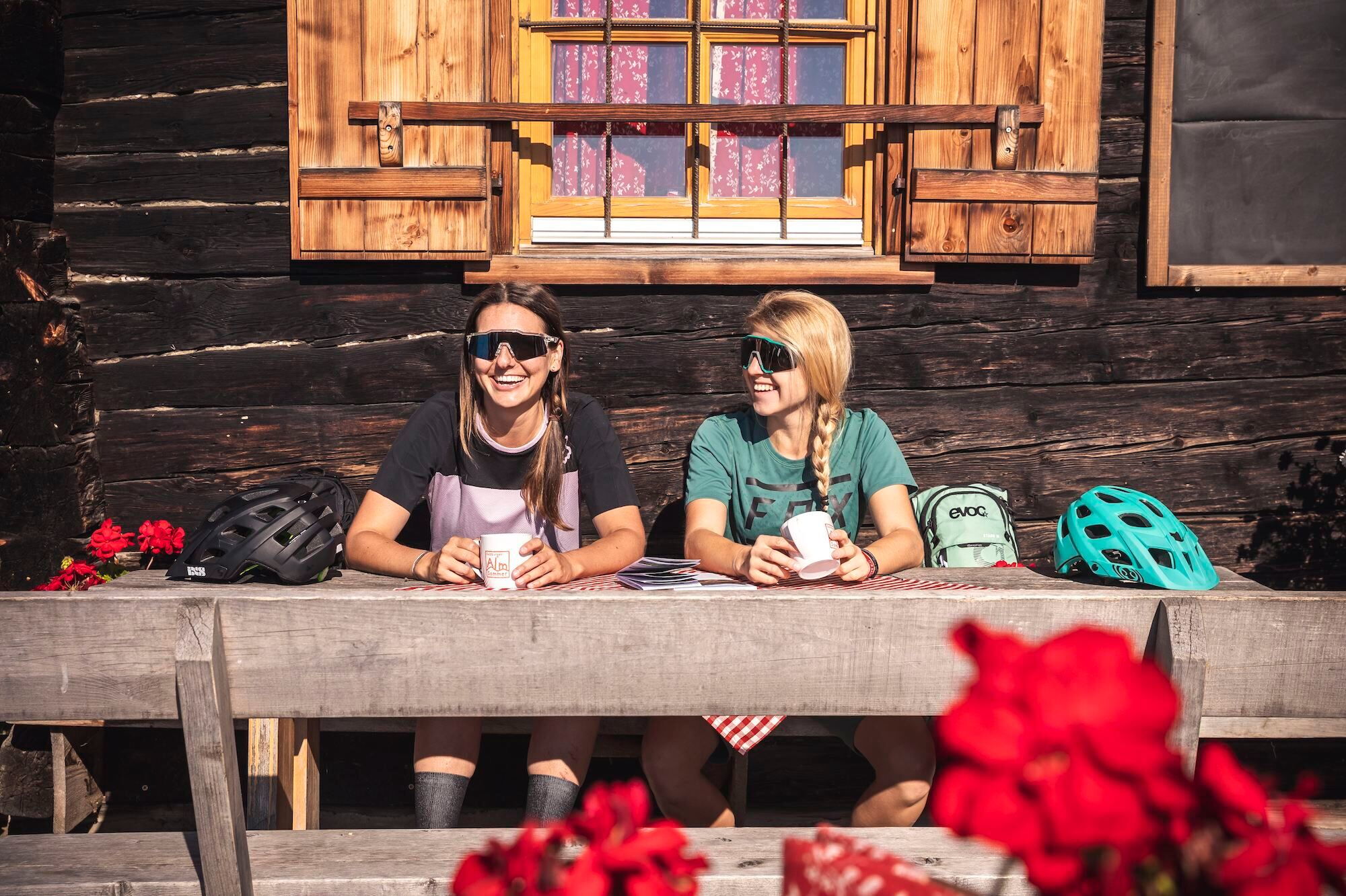 zwei Frauen sitzen auf einer Hütte in Hinterglemm nebeneinander udn trinken eine kaffee