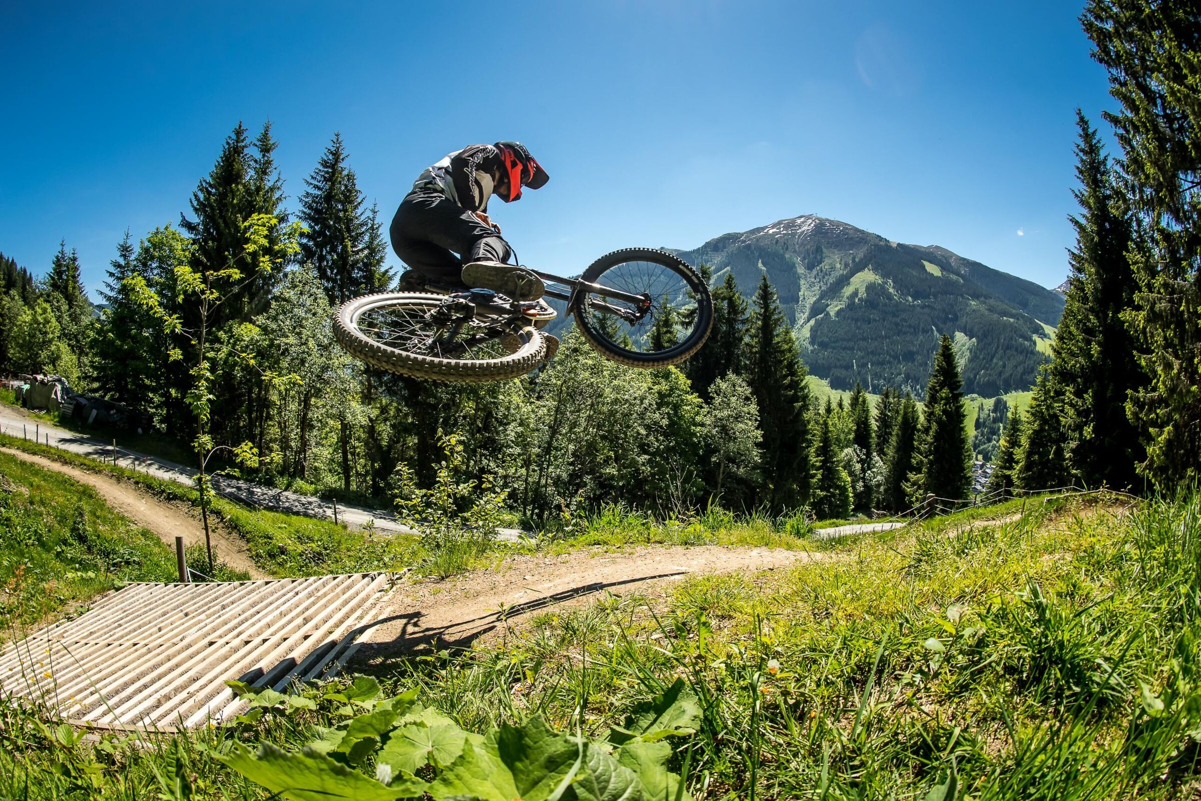 Downhill Mountainbiker springt über einen Sprung in alpiner Kulisse