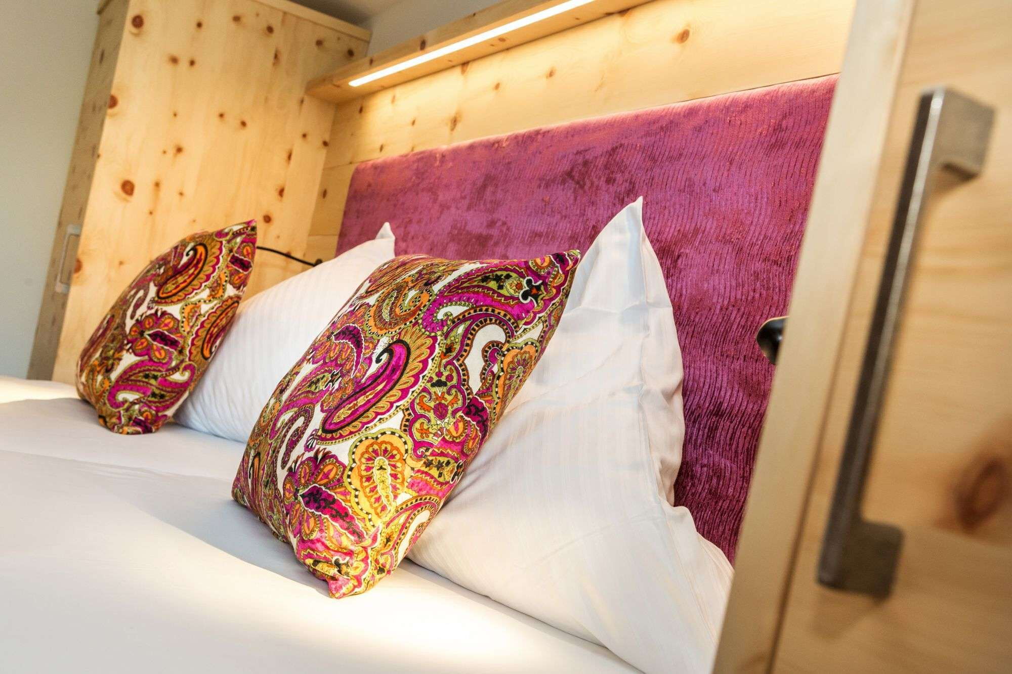 Bunte Kissen liegen auf dem Doppelbett im Zirbenzimmer im Hotel Talblick, Hinterglemm