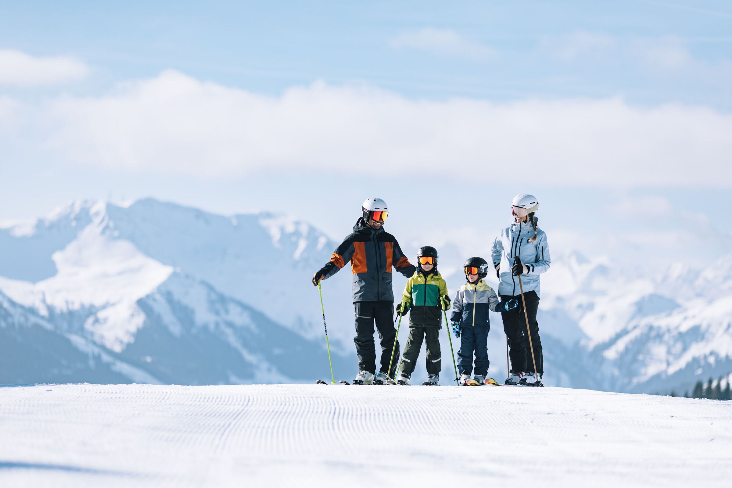 Zwei Erwachsene und zwei Kinder auf einer Skipiste in den Alpen