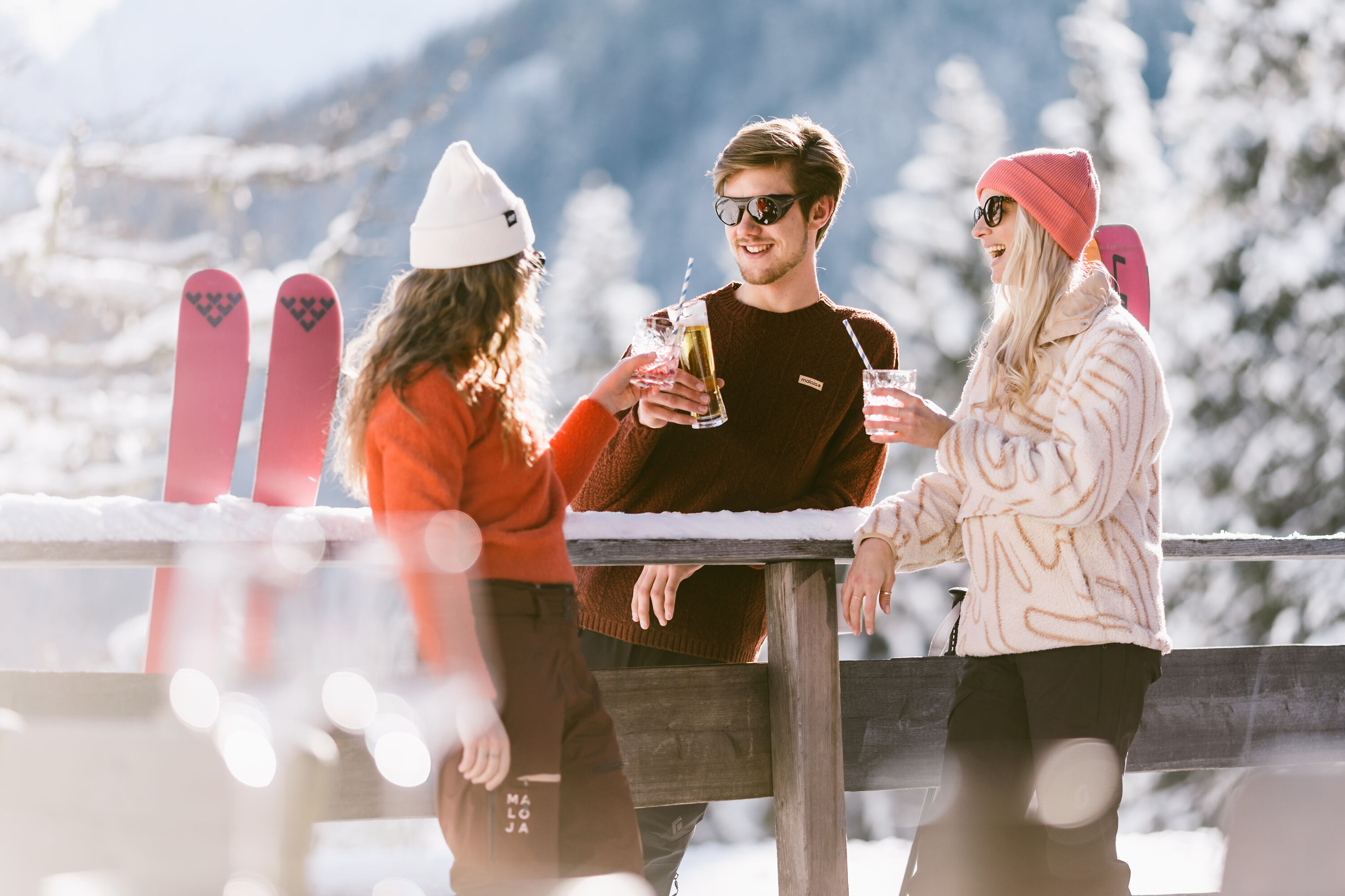 Drei Personen, die in winterlicher Landschaft ein Getränk genießen.
